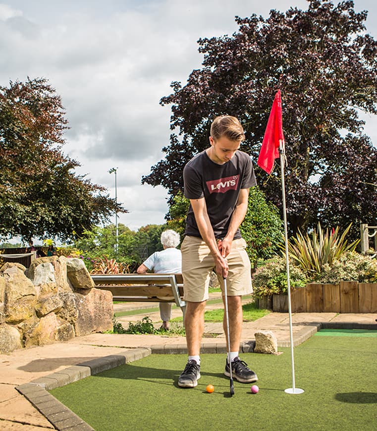 Boy playing mini golf
